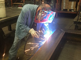 man welding a large metal beam